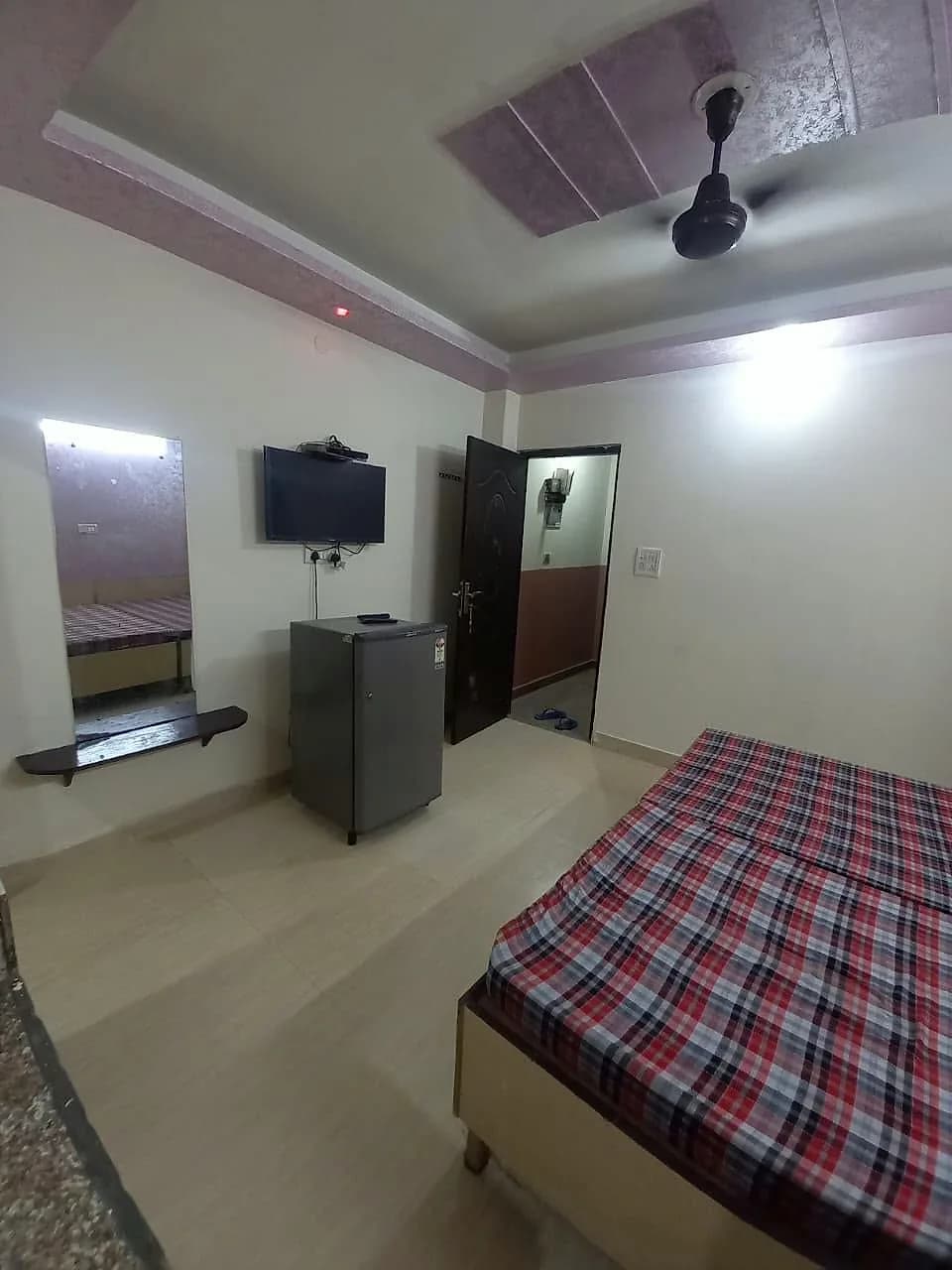 PG room with double bed, wall-mounted TV, refrigerator and mirror with shelf